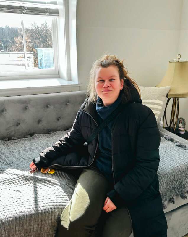 Camphill resident sitting on a couch in her apartment overlooking Hudson